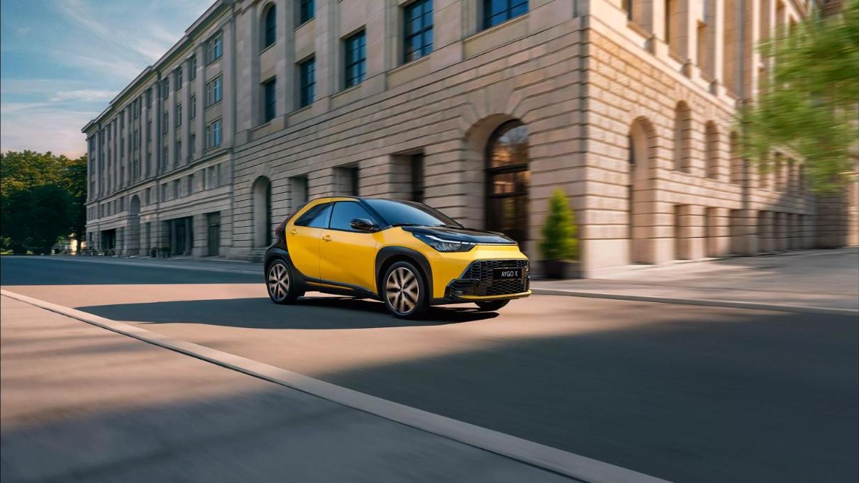 Yellow Toyota Aygo X driving on a city street